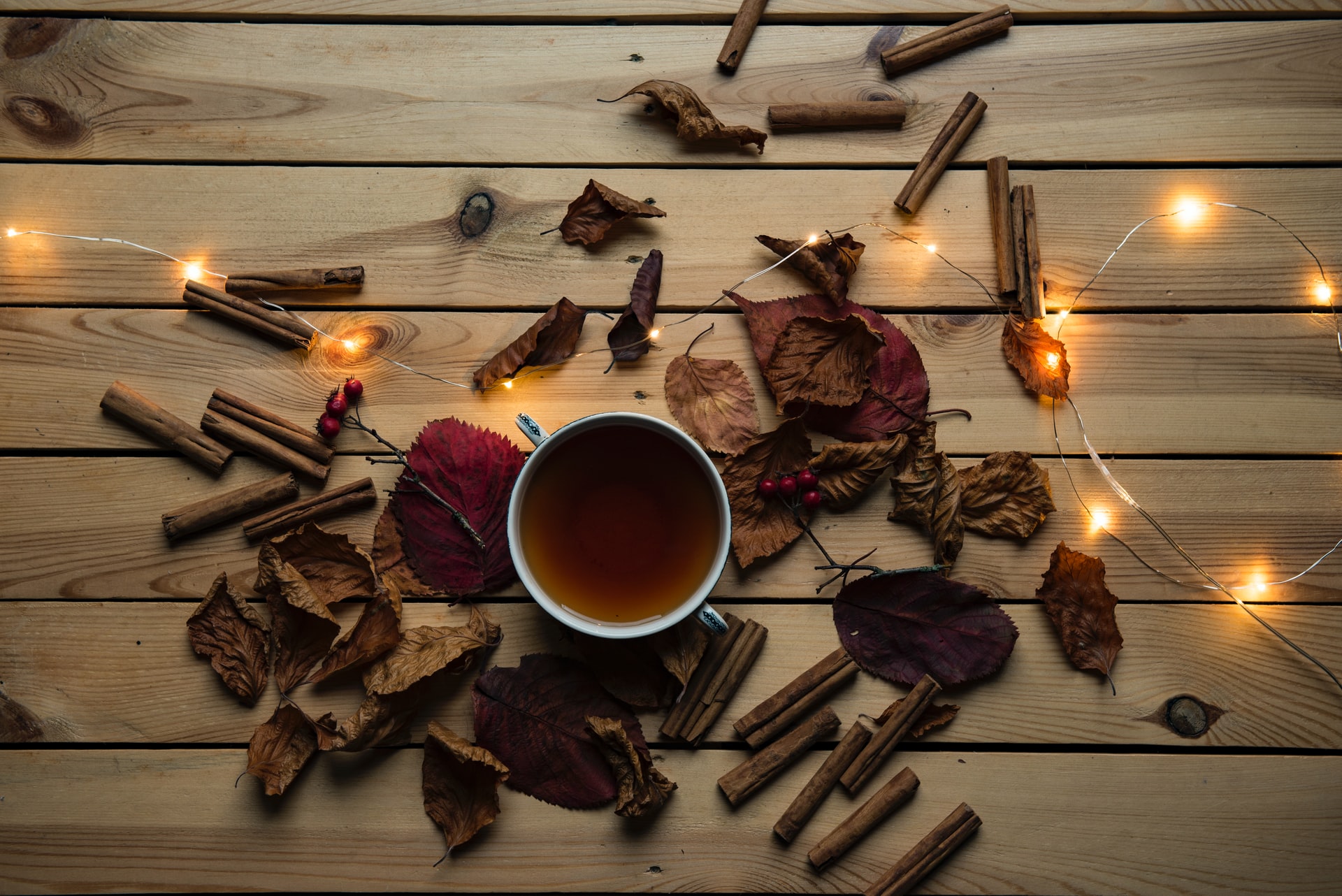 autumn flatlay with cinnamon sticks, twinkle lights, and a cup of tea