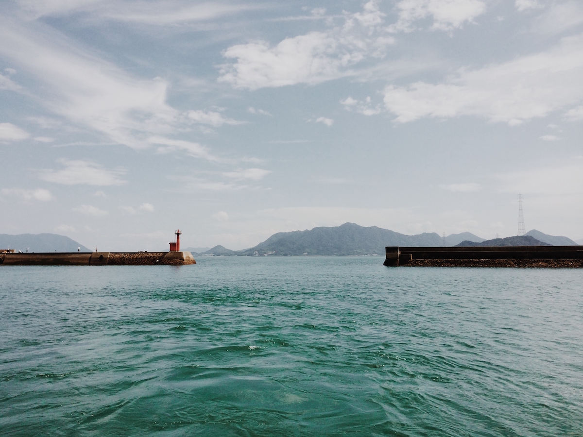 Turquoise waters and a distant mountain island during a ferry ride to Okunoshima