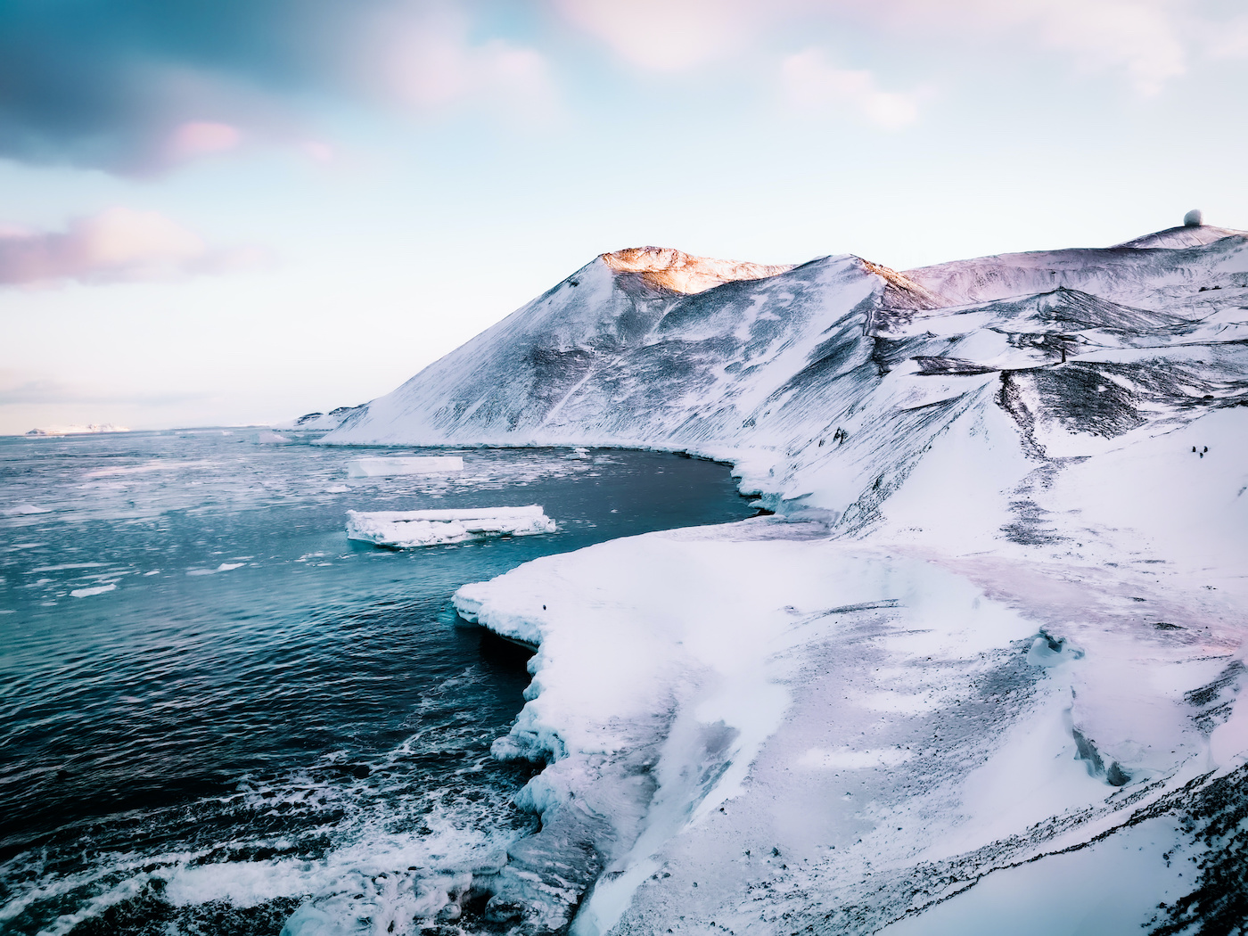 snowy hills with views of the frozen waters and icebergs at Ross Island, by McMurdo Station Antarctica