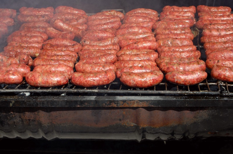dozens of choripan (sausages) cooking on a grill
