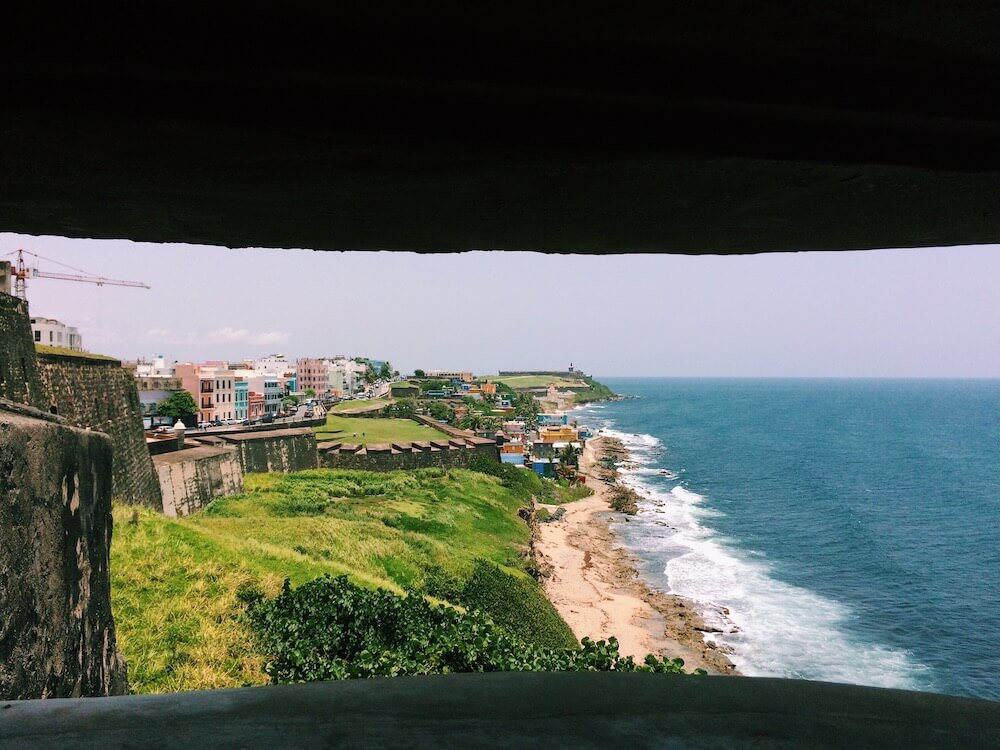 The view of the ocean, La Perla neighborhood, and El Morro Fort in the distance from a lookout point in Castillo de San Cristobal