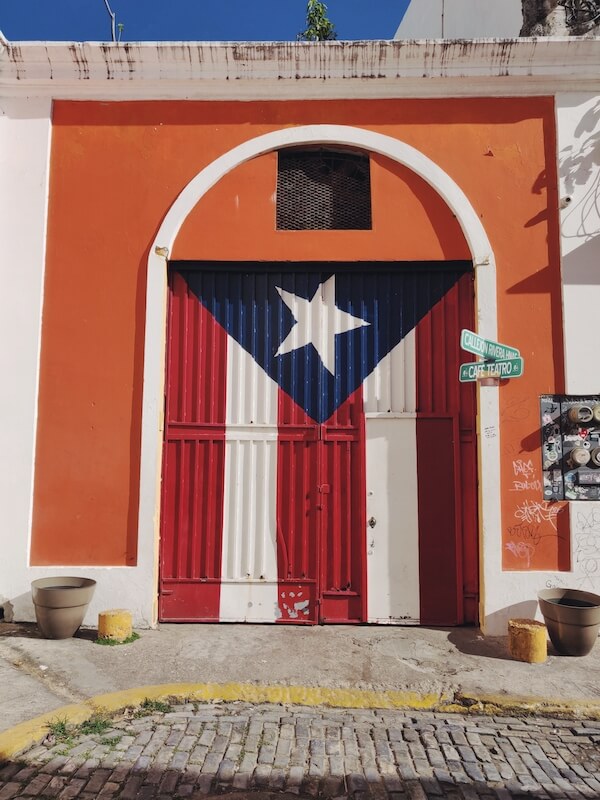 mural of puerto rican flag on side of orange building in flag alley