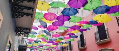 Famous Instagram street in Old San Juan known as Umbrella Street or Calle de Fortaleza; colorful umbrellas hang over the street outside brightly painted buildings