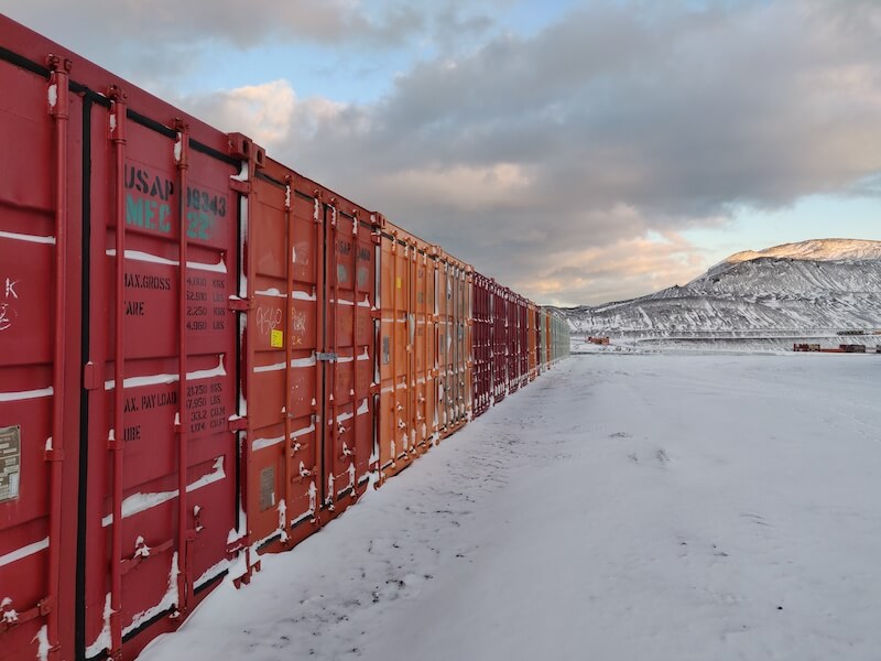 large red and orange shipping containers lined up on ice in Antarctica