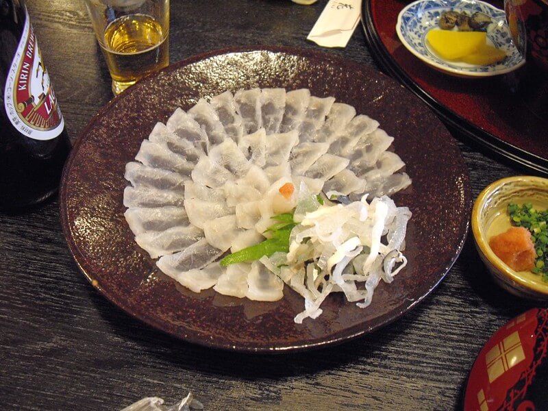 slices of opaque white fugu sashimi on a plate