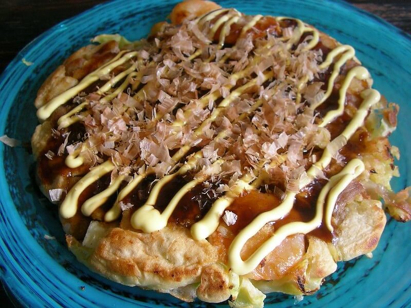 popular Japanese food okonomiyaki, a savory pancake, topped with sauces and bonito fish flakes