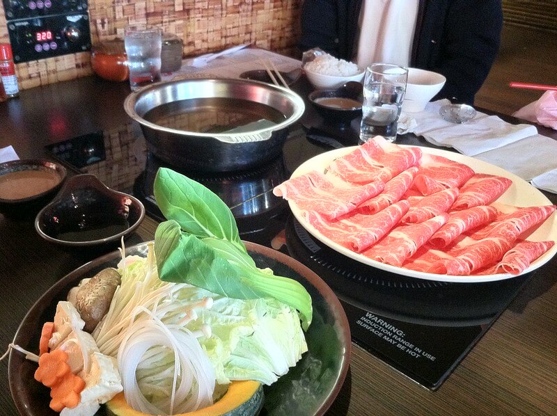 shabu shabu table, with slices of meat and vegetables waiting to be cooked