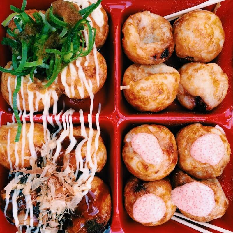 one of the 50 most popular japanese food, takoyaki (octopus balls). 4 varieties presented in a red, sectioned container