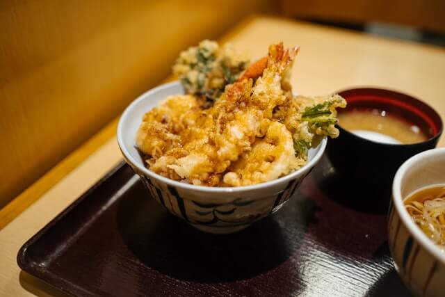 shrimp and vegetable tempura in a bowl next to soup