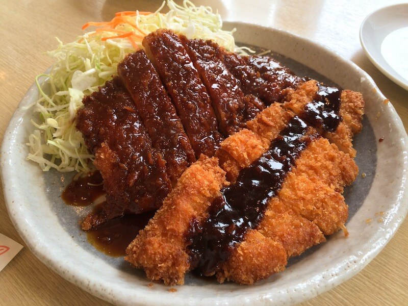 top japanese food tonkatsu pork cutlets served on a plate with sauce and shredded cabbage