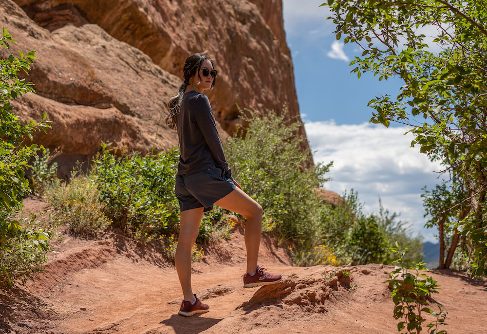 Girl standing in Red Rocks Park wearing KUHL's Konstance Sun Protection Long Sleeve in gray and blue Freeflex Hiking Shorts.