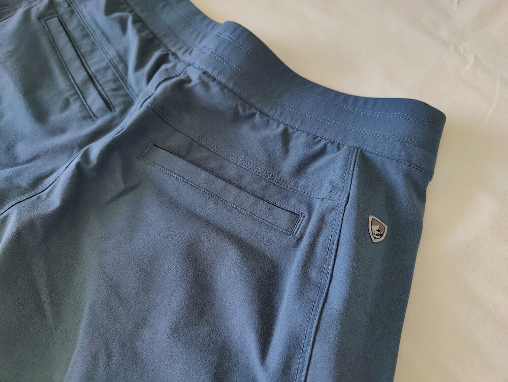 The backside of the KUHL Freeflex Hiking Short in Rainstorm blue. Photo shows the KUHL logo on the side of the shorts just below the waistband and the shorts' chino-style back pockets