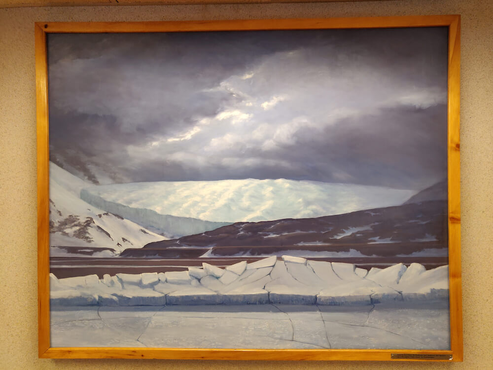 A painting of ice breaking with mountains in the background.