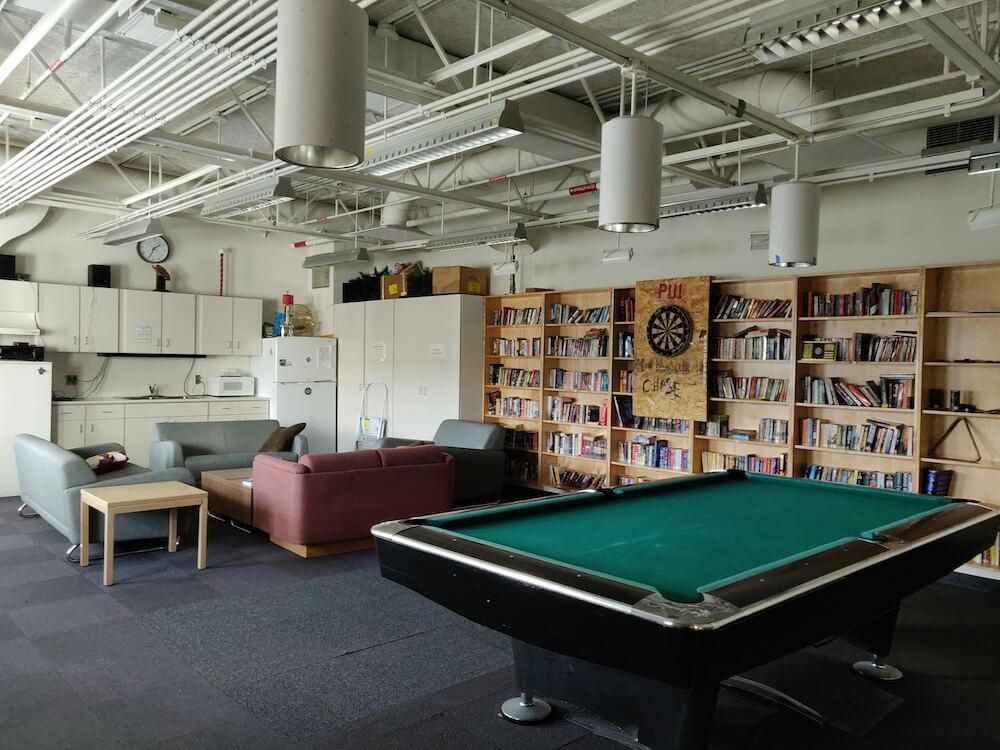 The game room and lounge at the South Pole. Pictured: a wall of books on shelves, a pool table, and couches
