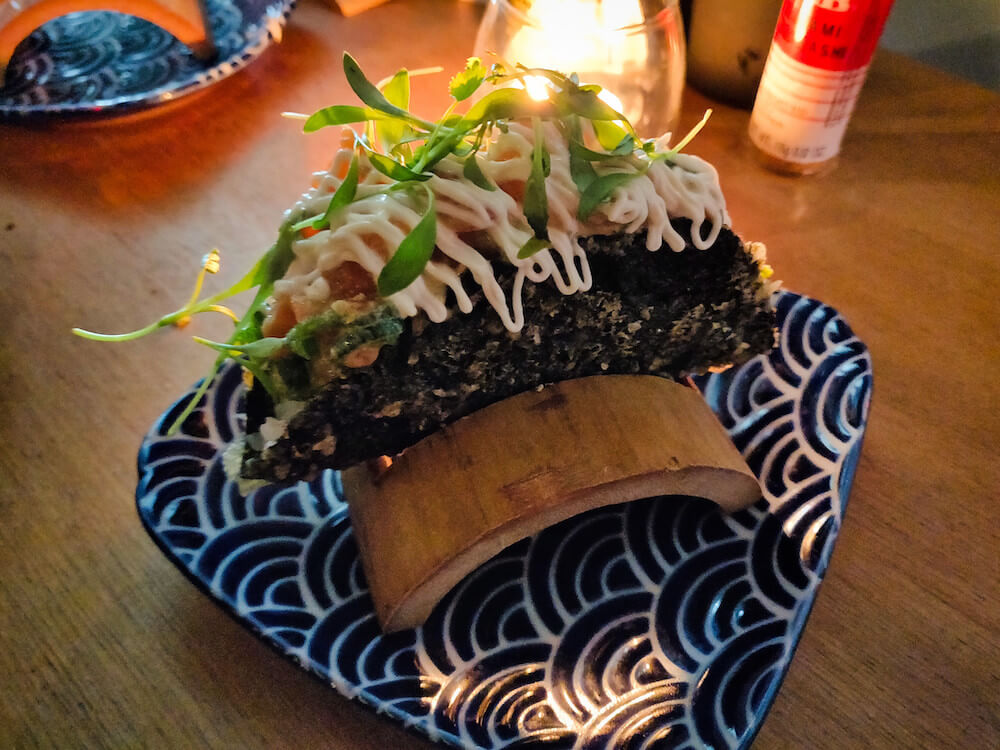 Bar Yoku's sushi taco: fried seaweed in the shape of a hard taco filled with rice and salmon, topped with Japanese mayo and greens