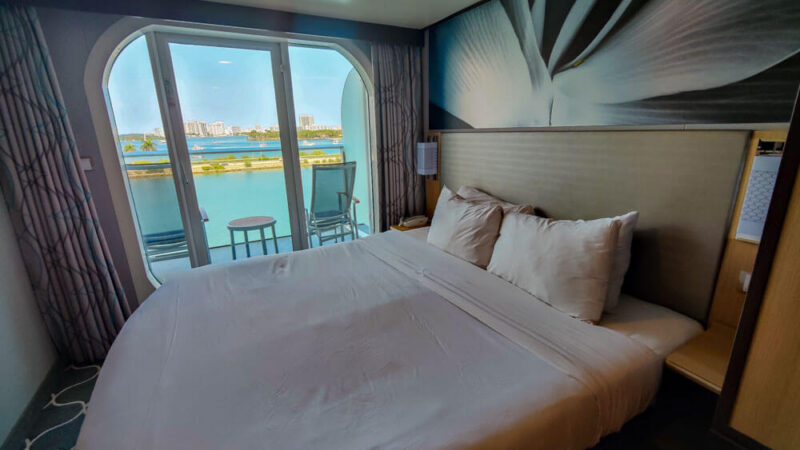 queen bed next to glass doors that lead out to ocean view balcony