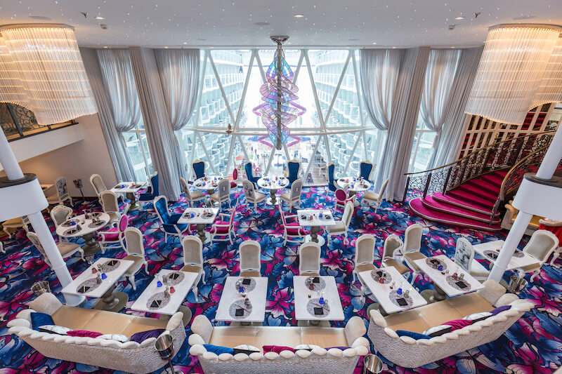 a colorful dining room with blue and pink carpet, staircase, and whimsical furniture