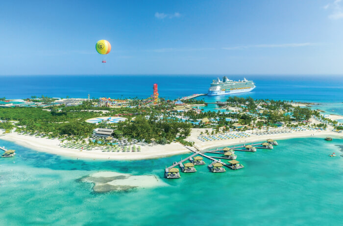 Aerial photo of Royal Caribbean's private island Cococay. Island includes a hot air balloon ride, water park, beaches and exclusive beach club, as well as overwater bungalows. An RCL ship is docked in the photo