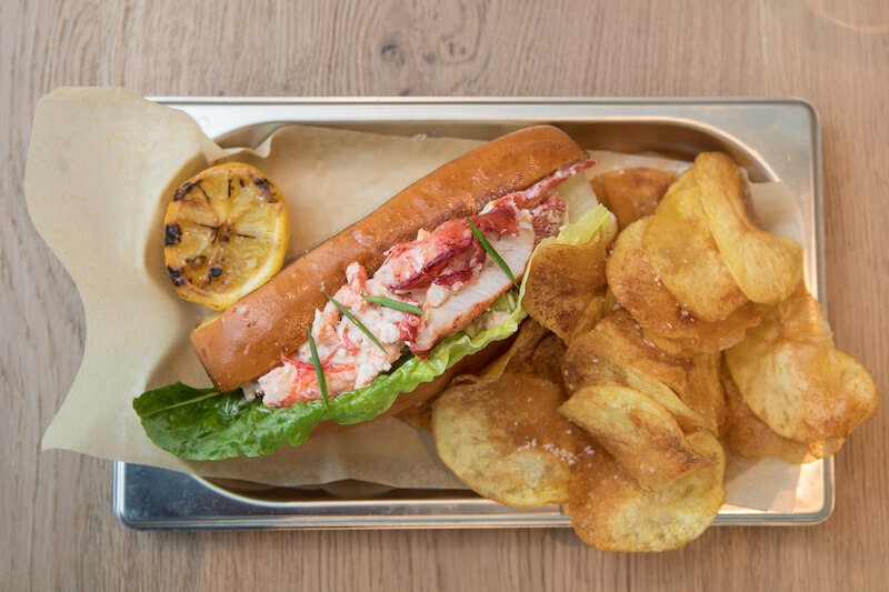 Royal Caribbean's Hooked Seafood featuring a lobster roll, chips, and a grilled slice of lemon
