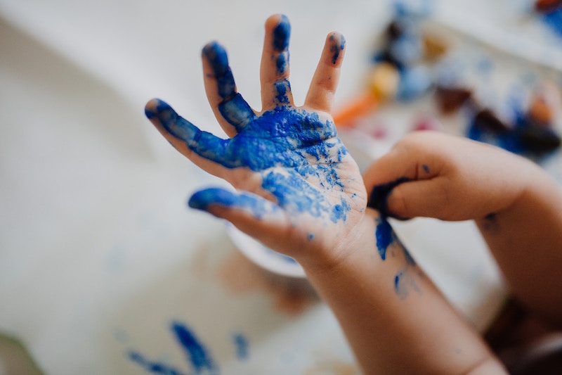 A child's hand covered in blue fingerpaint