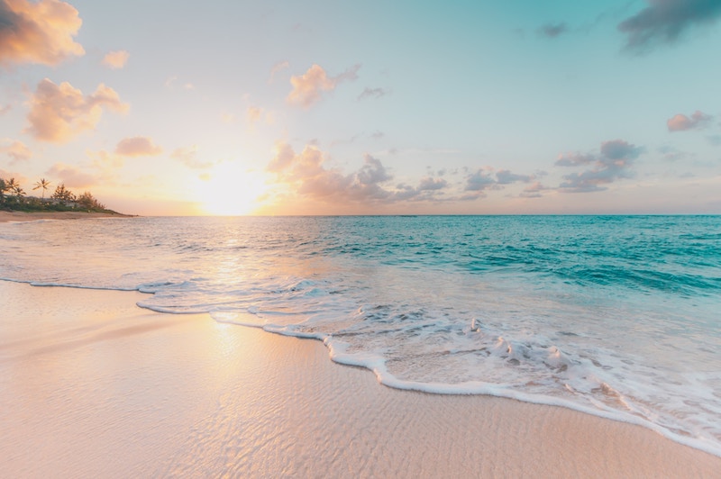 beach with clear blue water and white sand during sunset