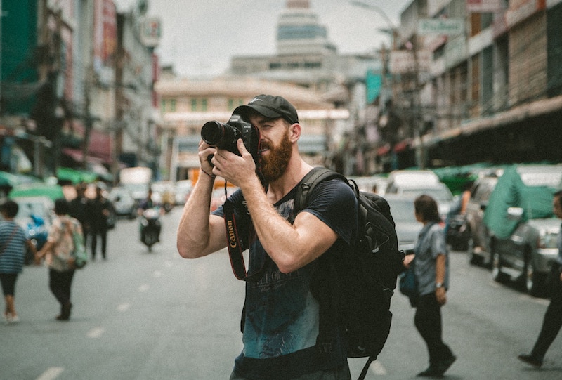 A man takes a photograph in the middle of the street