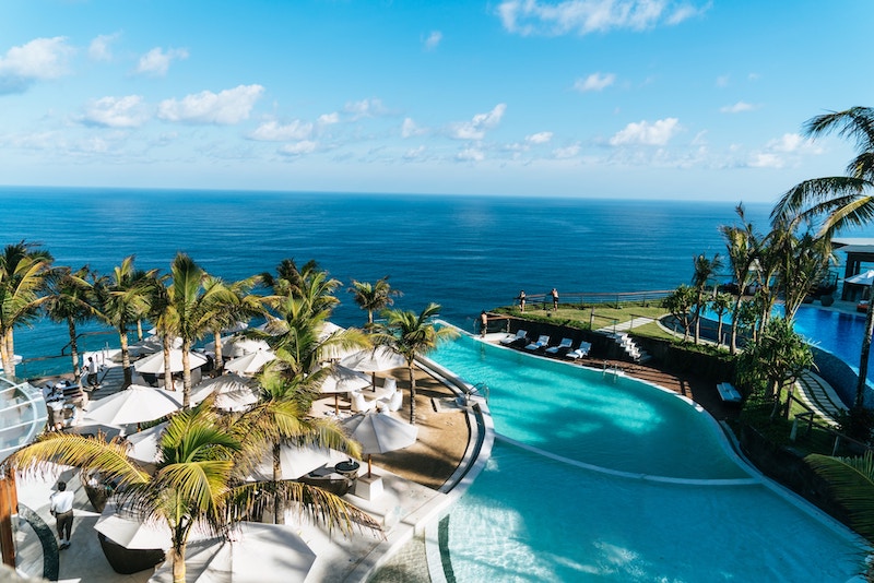 Aerial view of a luxury resort by the ocean with palm trees and pool. Working at a resort is a great option for jobs that travel with no experience