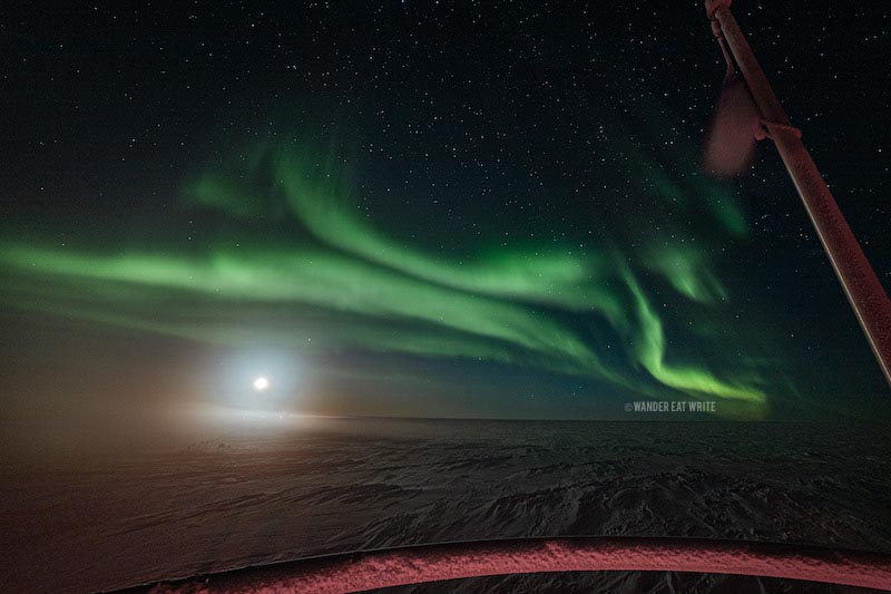 Southern lights in Antarctica: the moon and green auroras above it from the Observation Deck of the South Pole Station
