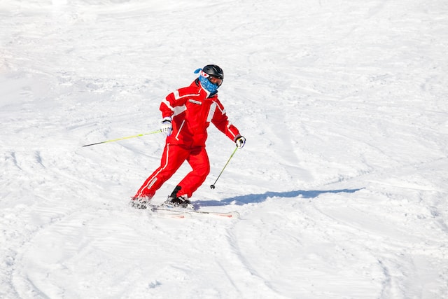 A person dressed in red winter gear, goggles, and a helmet skis down a slope in Niigata, Japan