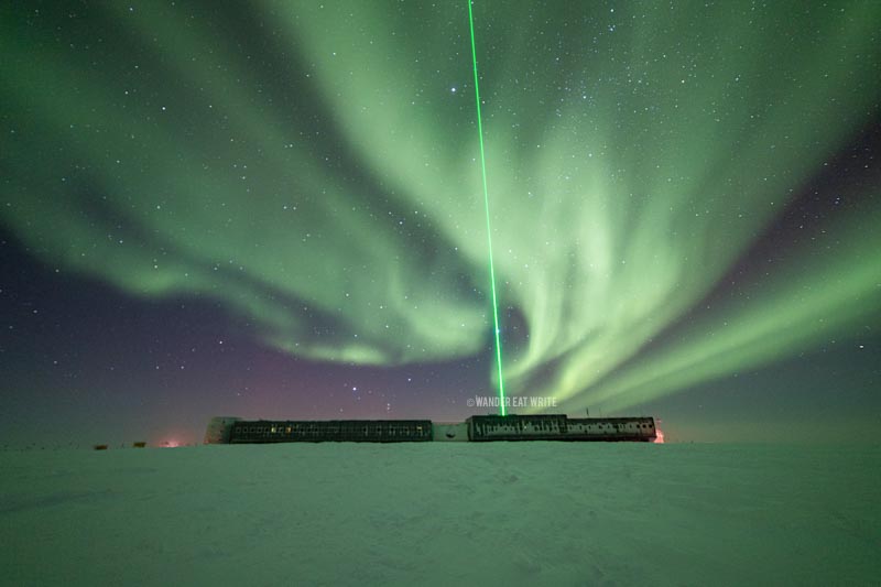 Bright green southern lights (not northern lights) in antarctica light up the sky and ground in front of amundsen-scott south pole station