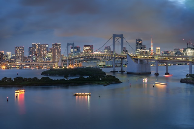 Tokyo Bay at night . The photo shows a bridge, the Tokyo Tower, city skyline, and small boats in the water
