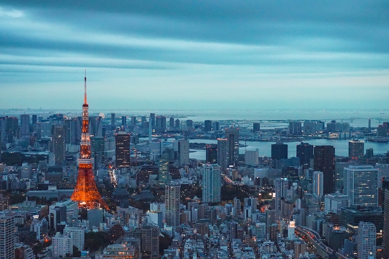Tokyo Tower, a red tower modeled after the Eiffel Tower, pictured amongst Tokyo's skyline at dusk