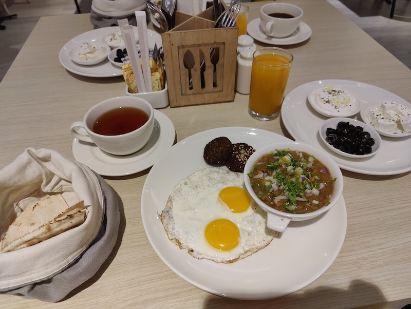An Arabic breakfast at the Swiss-Cafe: tea, mango juice, Arabic flatbread, sunny side up eggs, falafel, ful medames, feta cheese with olives, labneh
