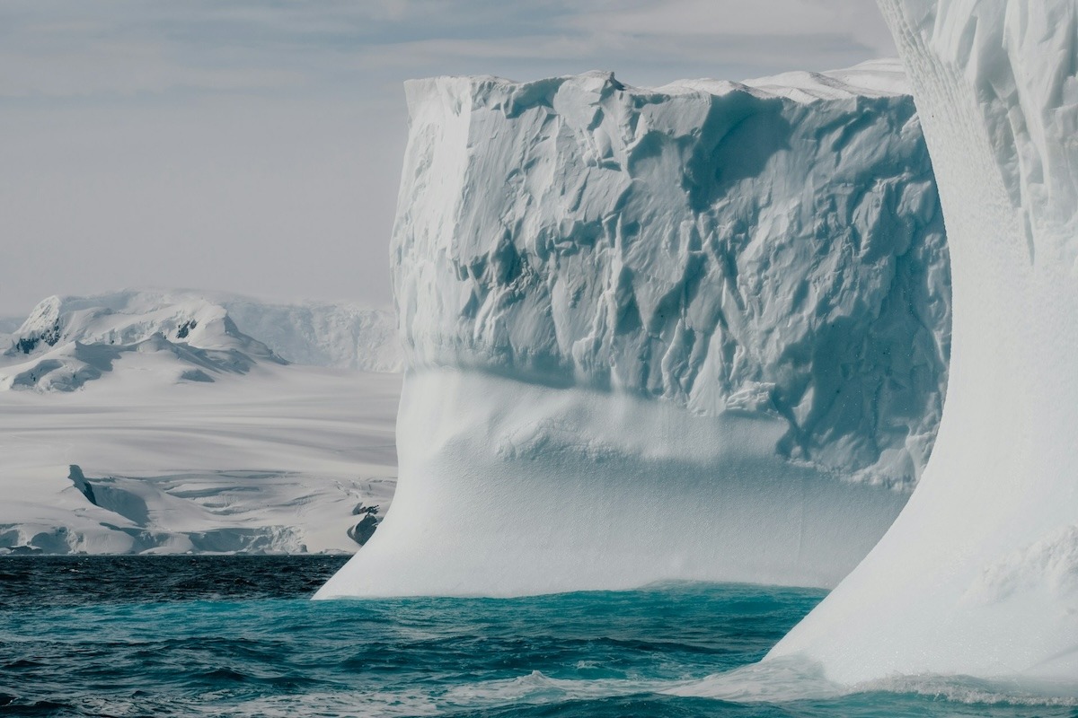 A large white iceberg in the teal Antartica waters