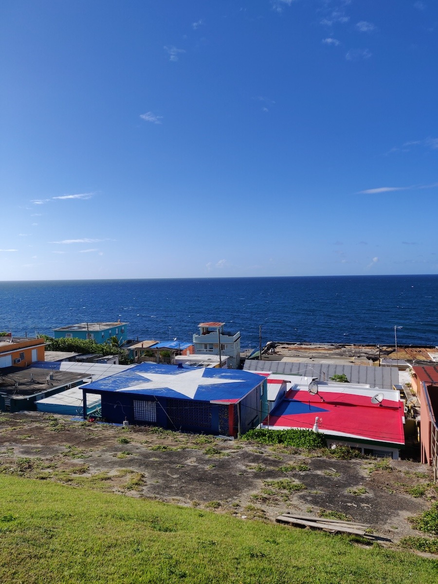 The Puerto Rican flag is painted on the roof of a building by the ocean