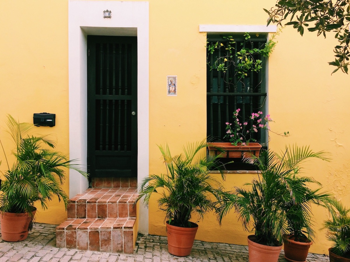 A brightly painted yellow home in San Juan, Puerto Rico with tropical plants in the front