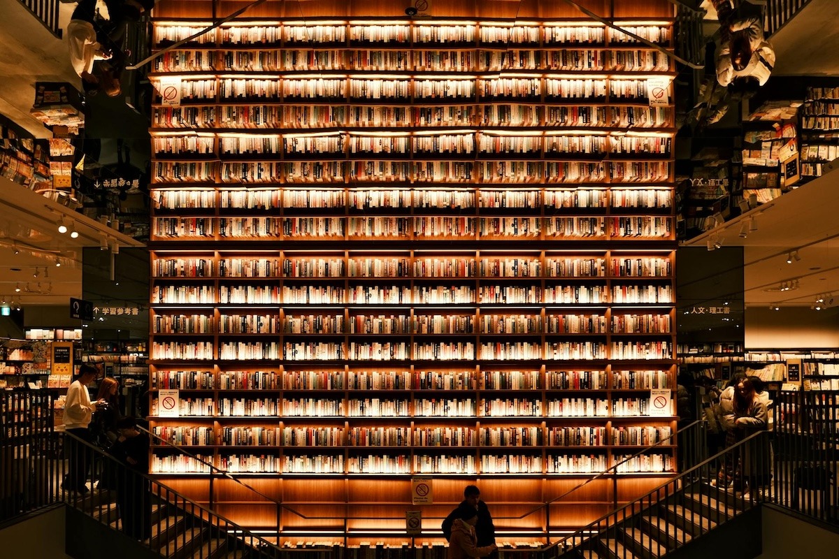 A 2-story bookcase wall at a bookstore lit up