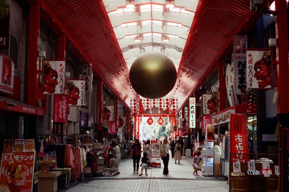 Osu Street in Nagoya, Japan: a covered shopping arcade that's painted red, also with stores signs and banners also in red. A large bolden ball hangs from the celiing