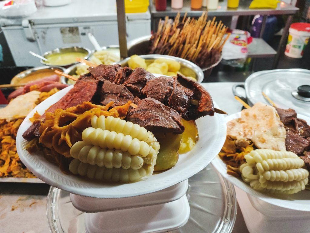 A plate of anticucho, choclo, and potatoes