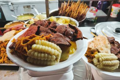 A plate of anticucho, choclo, and potatoes