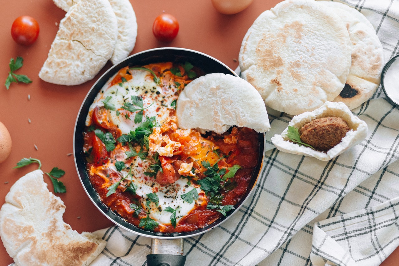 pan of shakshuka: poached eggs in tomato sauce; pita bread, and falafel