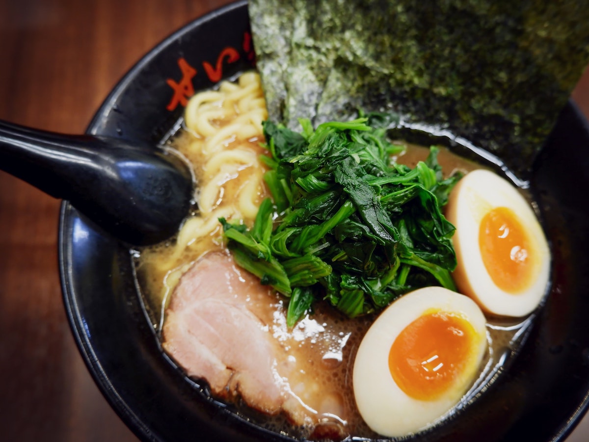 bowl of ramen including: boiled egg, spinach, seaweed, and pork