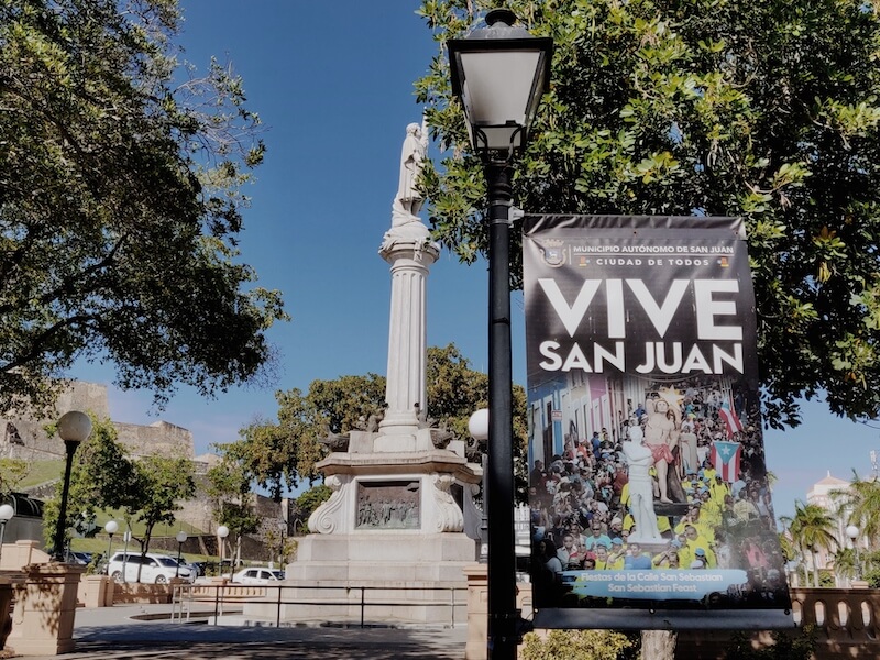 Statue of Christopher Columbus and light post with banner for event at Plaza Colon in San Juan