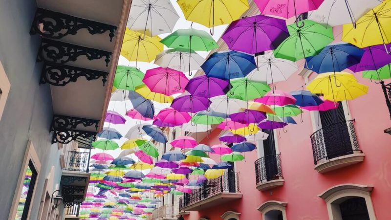 Famous Instagram street in Old San Juan known as Umbrella Street or Calle de Fortaleza; colorful umbrellas hang over the street outside brightly painted buildings