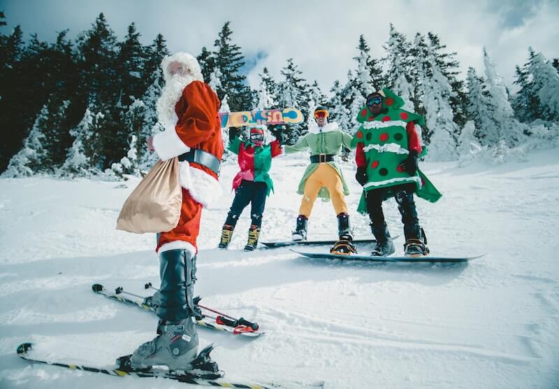 skiers on the slope wearing festive christmas costumes: santa, elves, and christmas tree