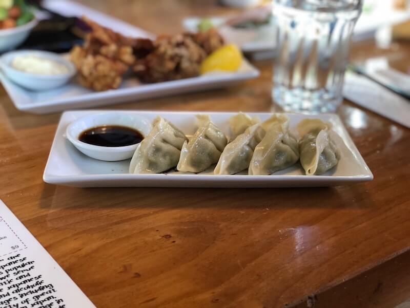 japanese gyoza on a white plate next to sauce