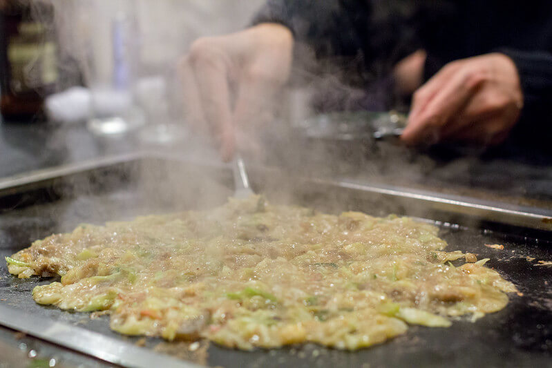 japanese food monjayaki, a thin savory pancake, being grilled