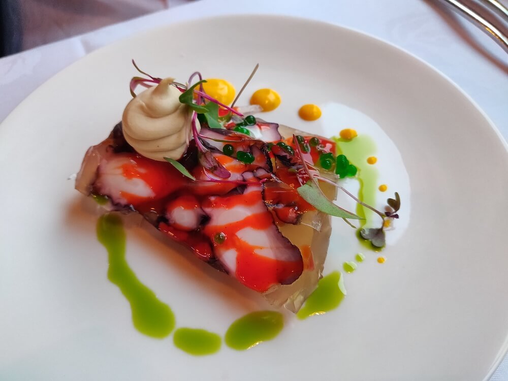 The octopus mosaic entree: slices of octopus jellied together with a green parsley dressing, saffron aioli, black garlic cream, watercress and lemongrass pearls