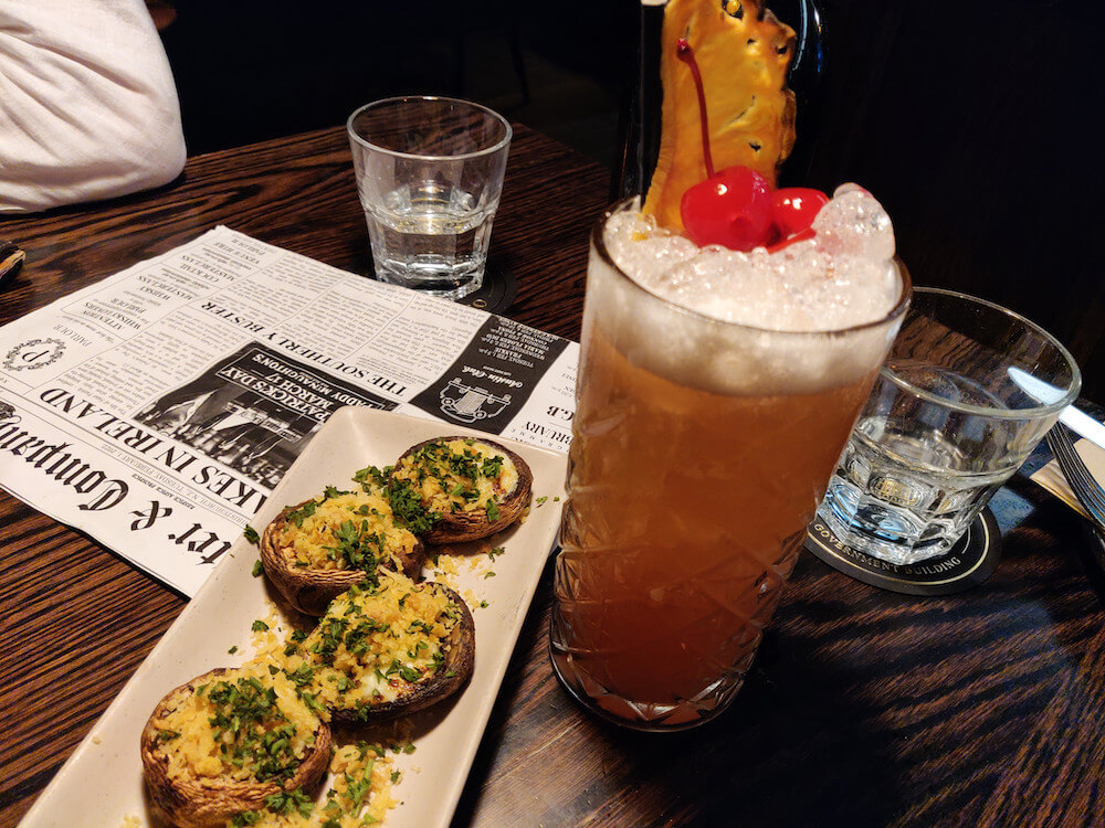 Stuffed mushrooms and cocktail on dark wood table at OGB Bar in Christchurch New Zealand