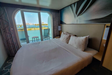 queen bed next to glass doors that lead out to ocean view balcony